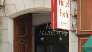 Ein Hotel Eingang mit einer Löwenstatue davor, einem Schild für Hotel Foch und der Nummer 59 an der Tür.