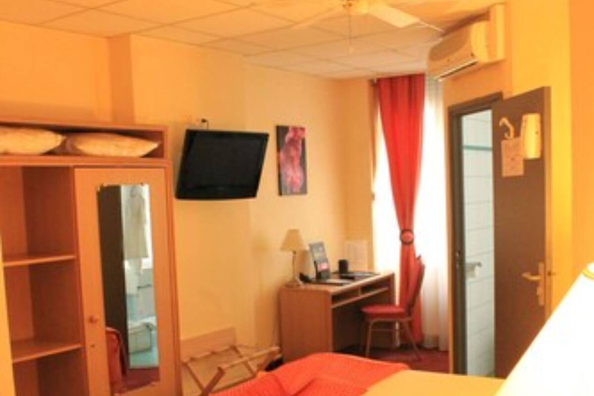 A hotel room with a bed, a desk, a chair, a TV, and a wardrobe.