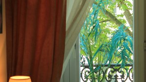 Ein Fenster mit Vorhang, einer Blumentopf und einem Balkongeländer.