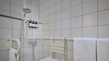 Ein Badezimmer mit Dusche, Handtuchhalter und einer Shampoo-Flasche.