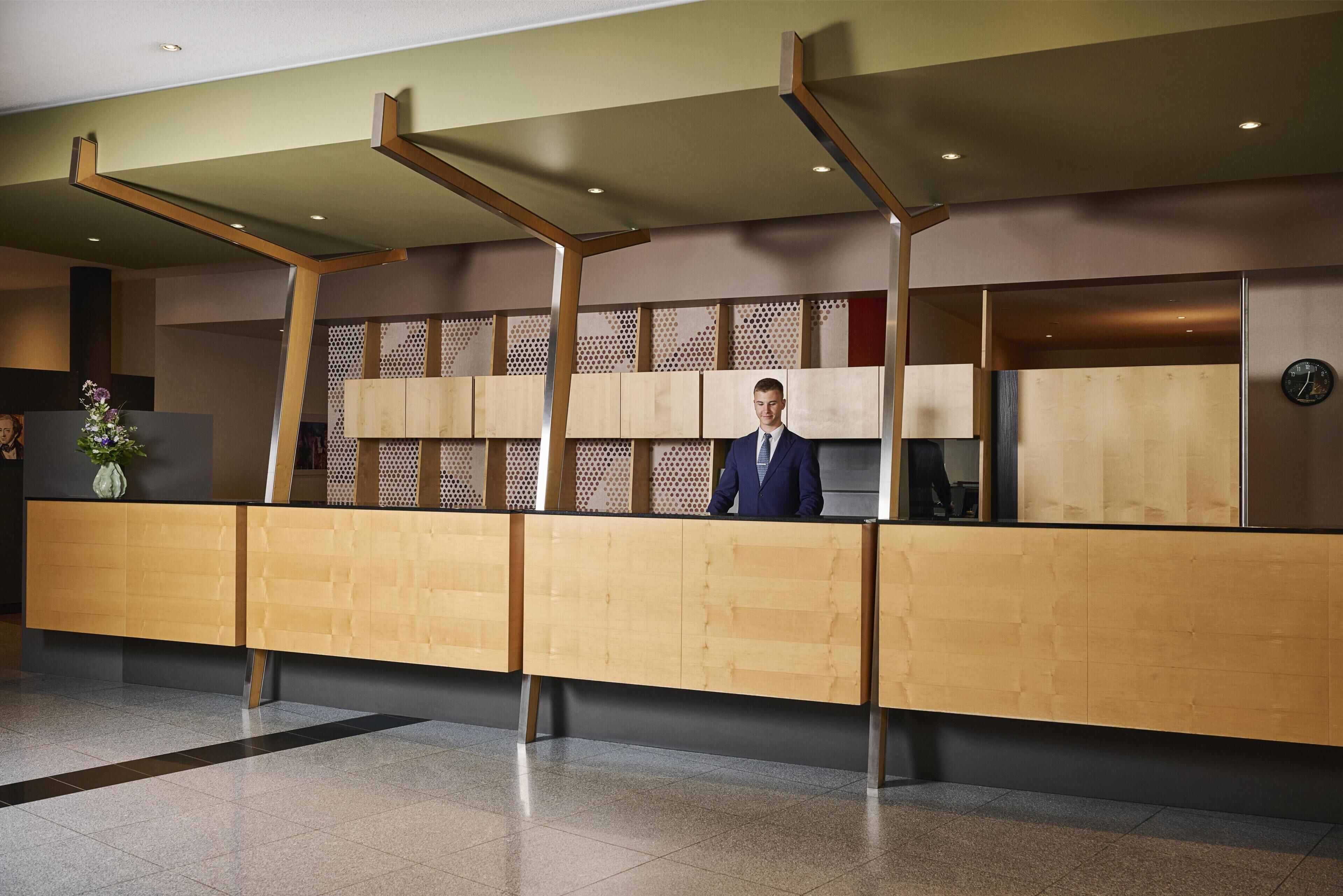 Een receptiebalie met een modern ontwerp, afgewerkt met hout en een patroonachtergrond.