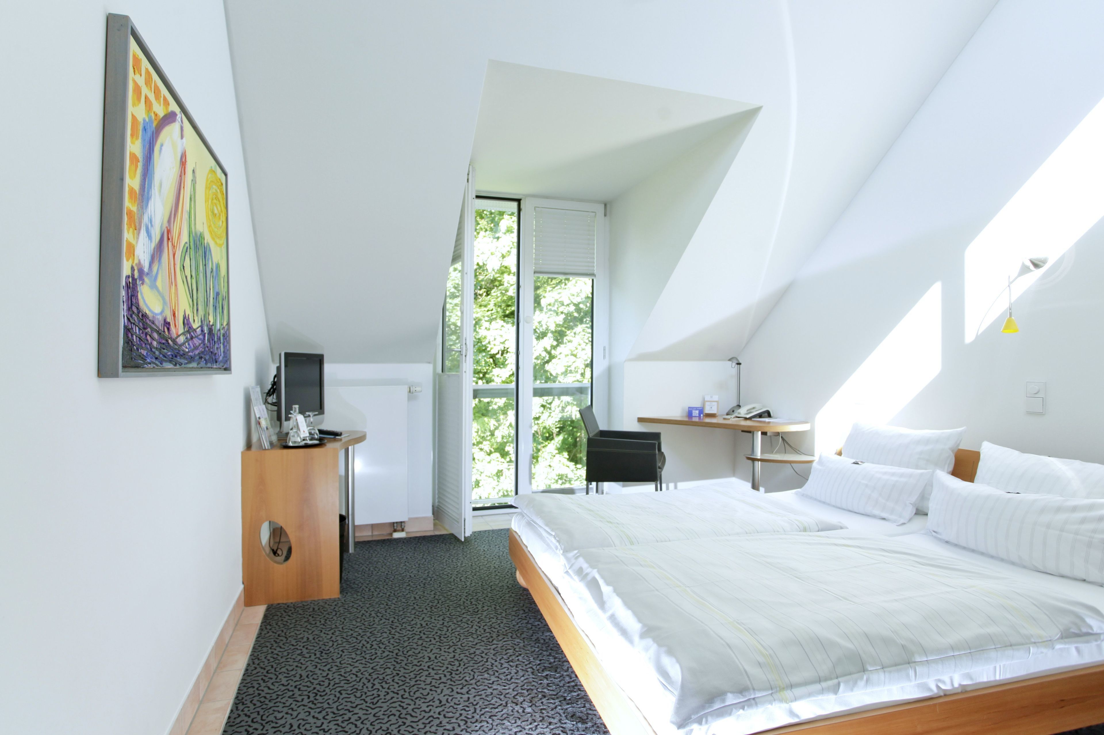 Un dormitorio con una cama grande, un escritorio, una silla, un radiador y una ventana.