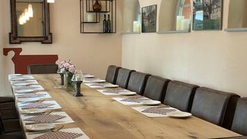 Una larga mesa de madera dispuesta para una comida, con platos, cubiertos y servilletas.