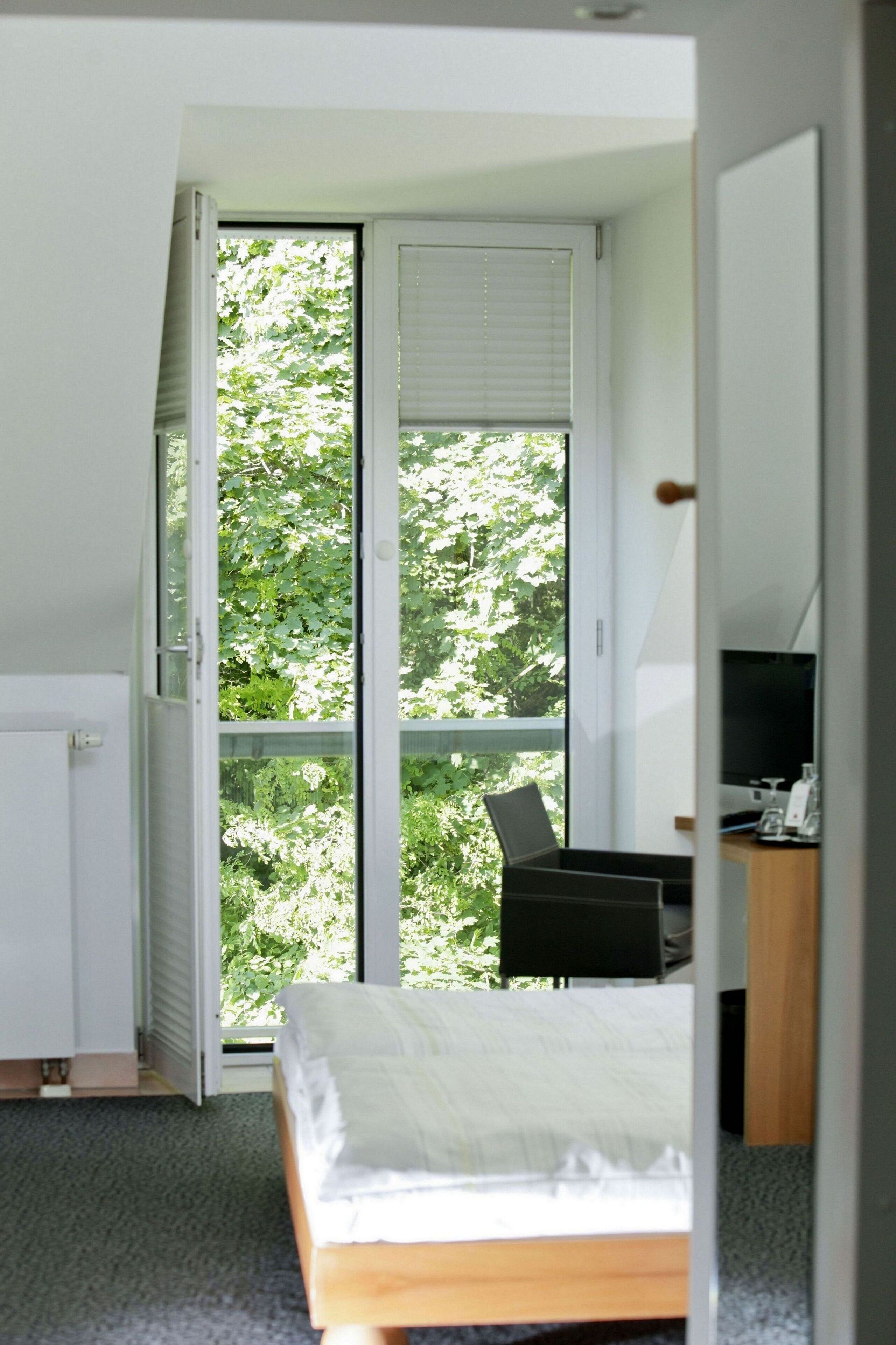 A bedroom with a bed, a desk with a chair, and a television.