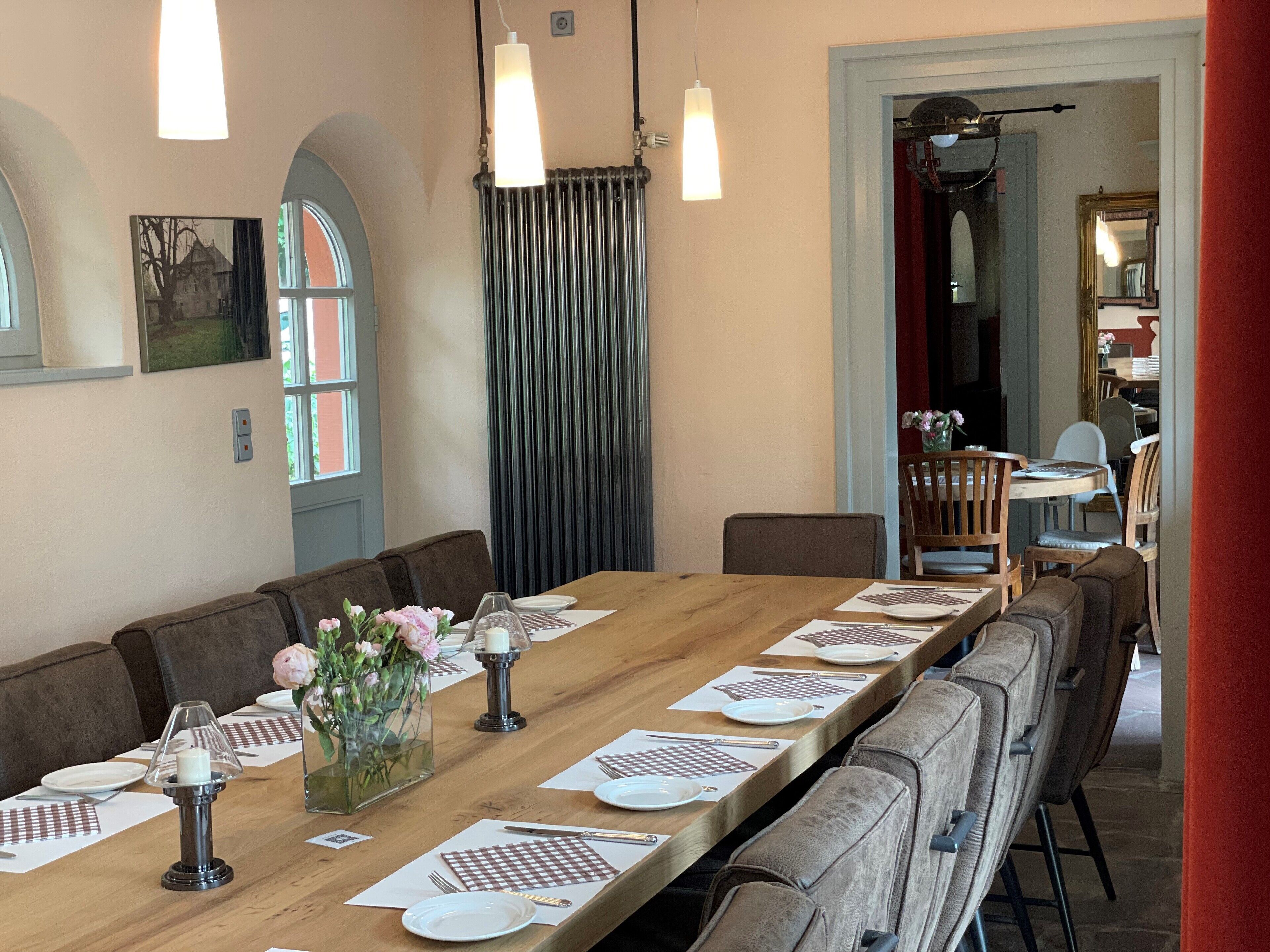 A dining area with a long wooden table set for a meal, flanked by cushioned chairs.