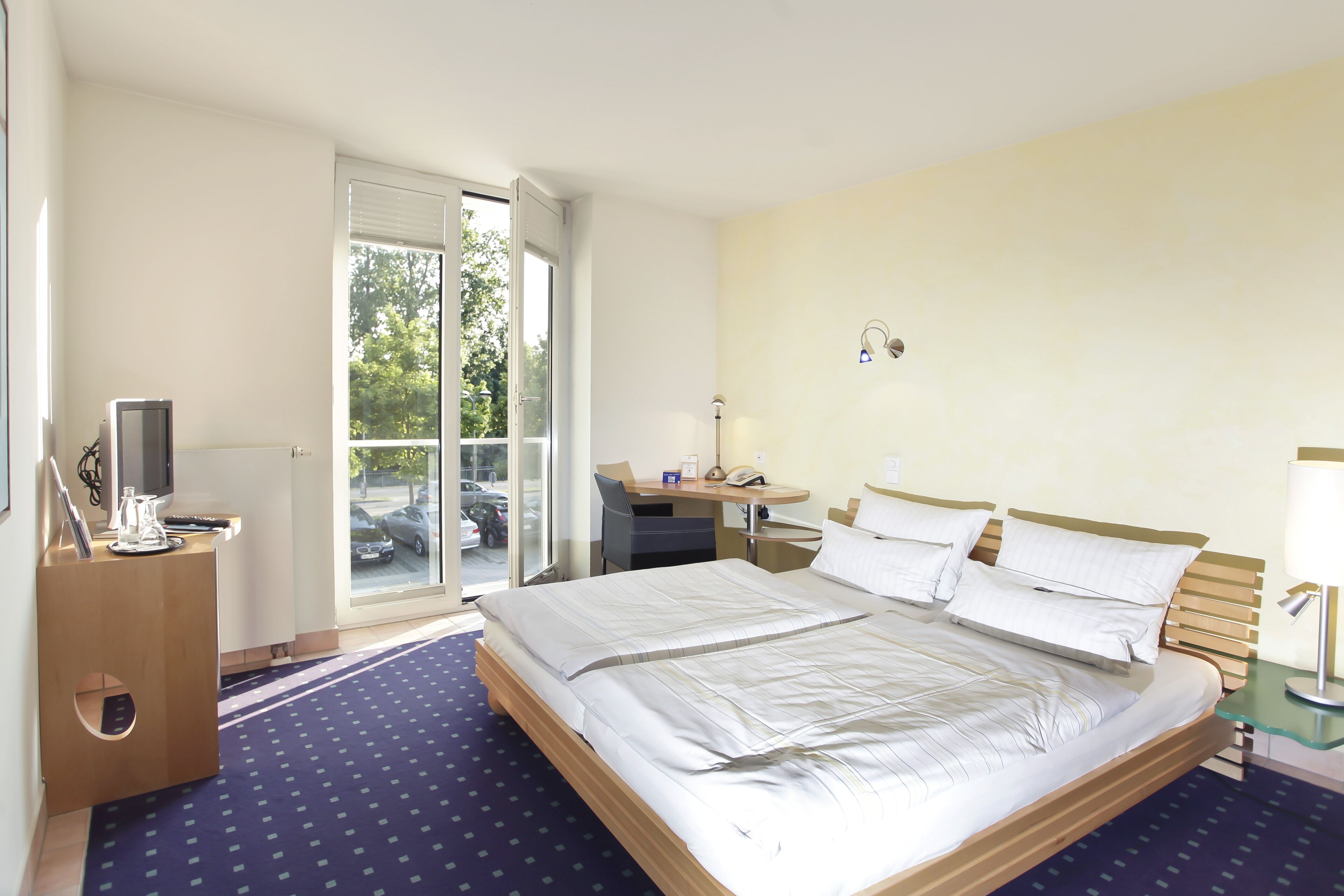 Une chambre d’hôtel équipée d’un lit, d’un bureau, d’une chaise et offrant une vue sur l’extérieur.