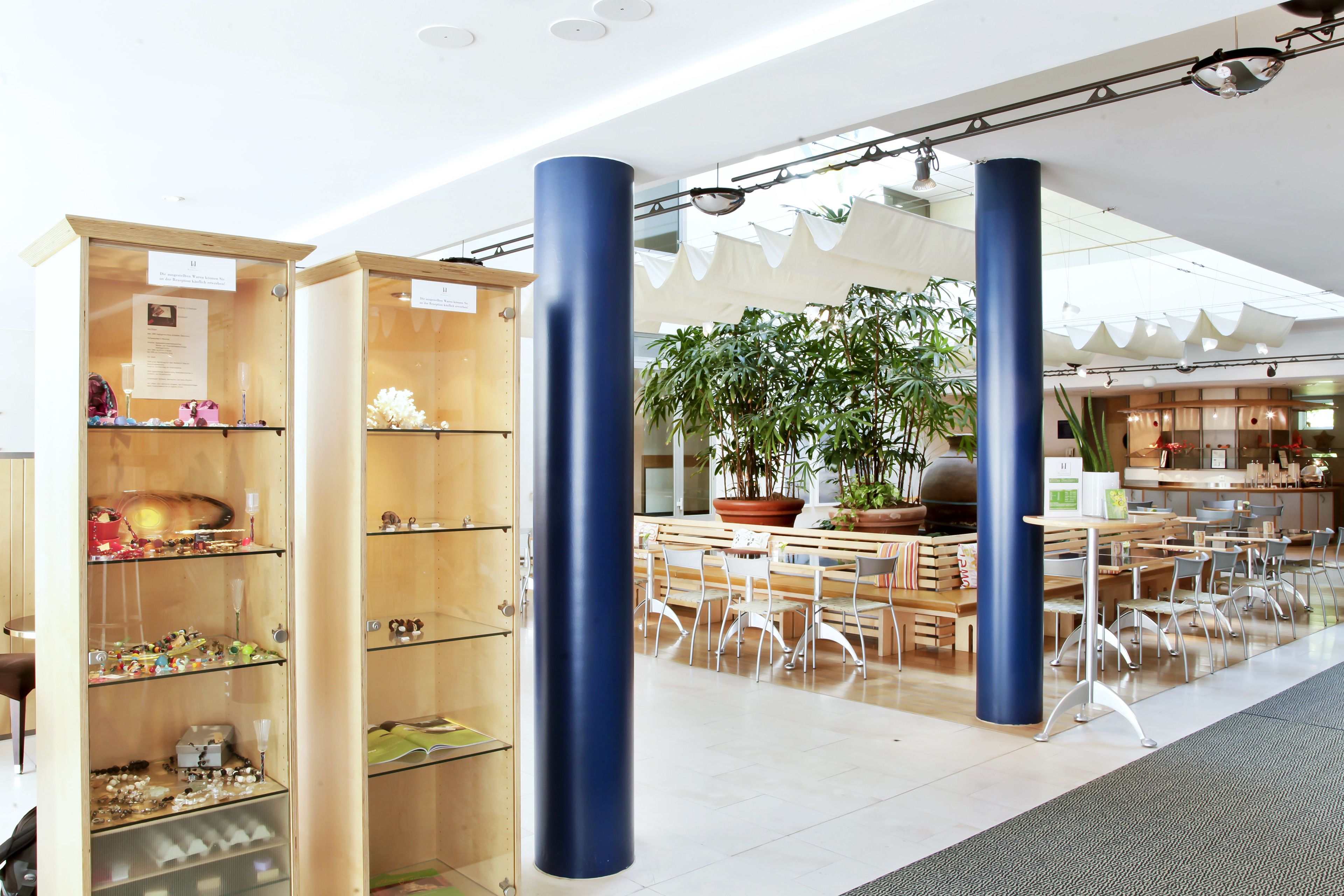 A spacious indoor area with wooden display cases, blue pillars, and a seating area with tables and chairs.