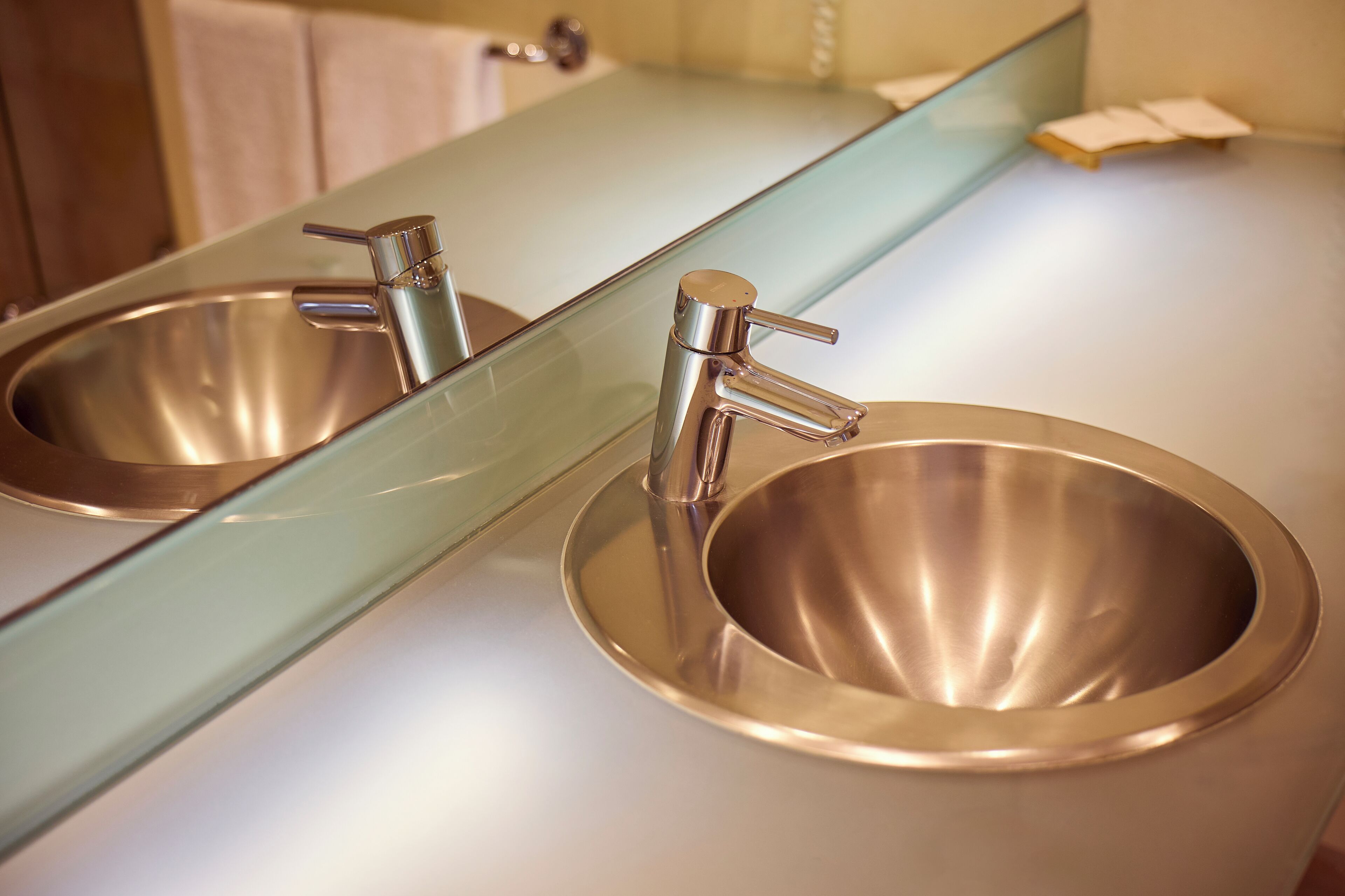Un baño con un lavamanos de acero inoxidable y un espejo encima.