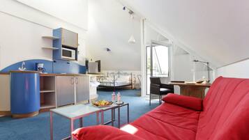 A compact living space with a kitchenette, a dining area, and a red sofa.