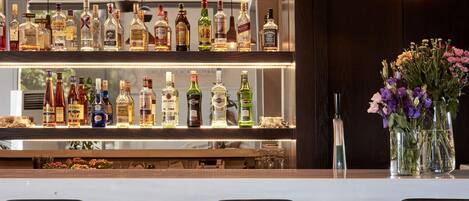 A bar area with shelves of liquor bottles and a vase of flowers.