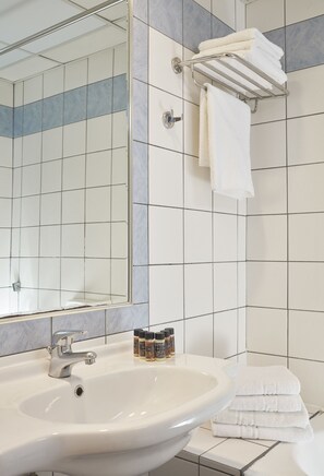 A bathroom with a sink, mirror, towel rack, and tiled walls.