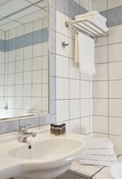 Casa de banho com lavatório, espelho, porta-toalhas e paredes em azulejo.
