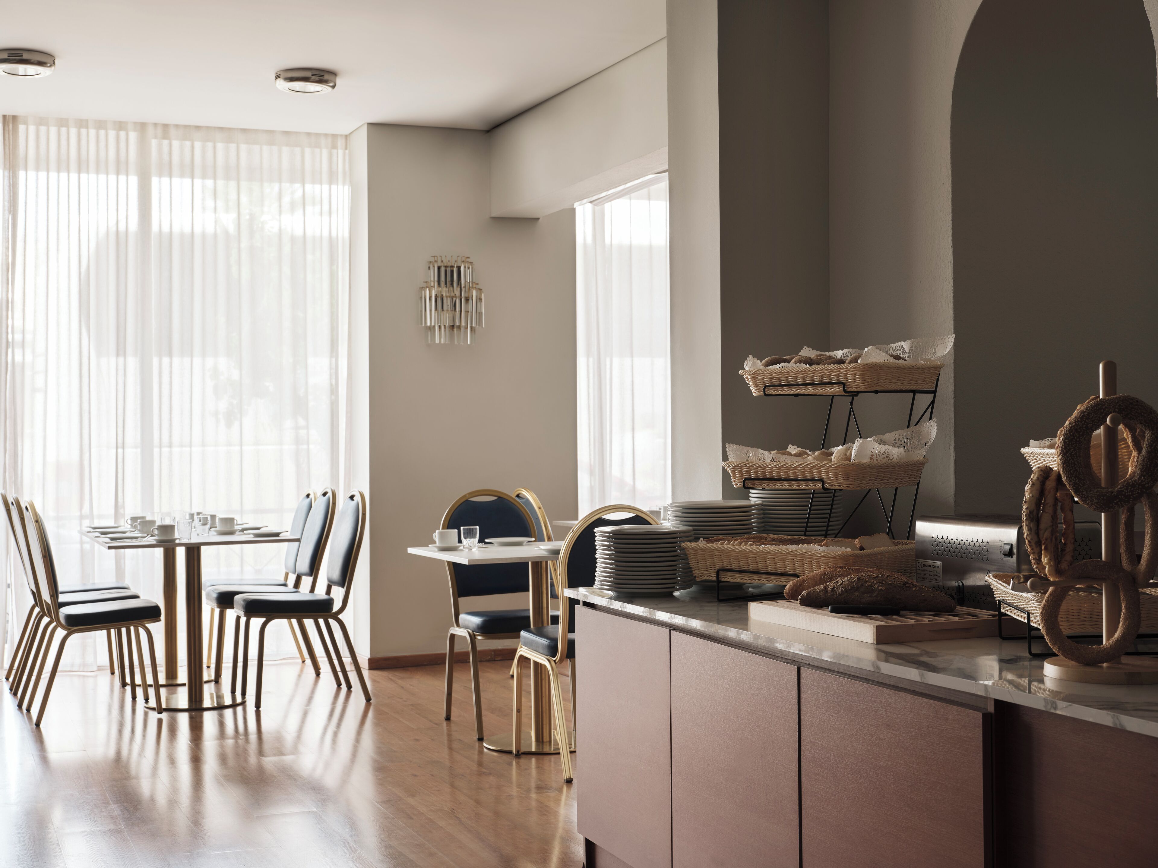 A modern kitchen with a dining area, featuring a central island with baskets and a hanging rack.