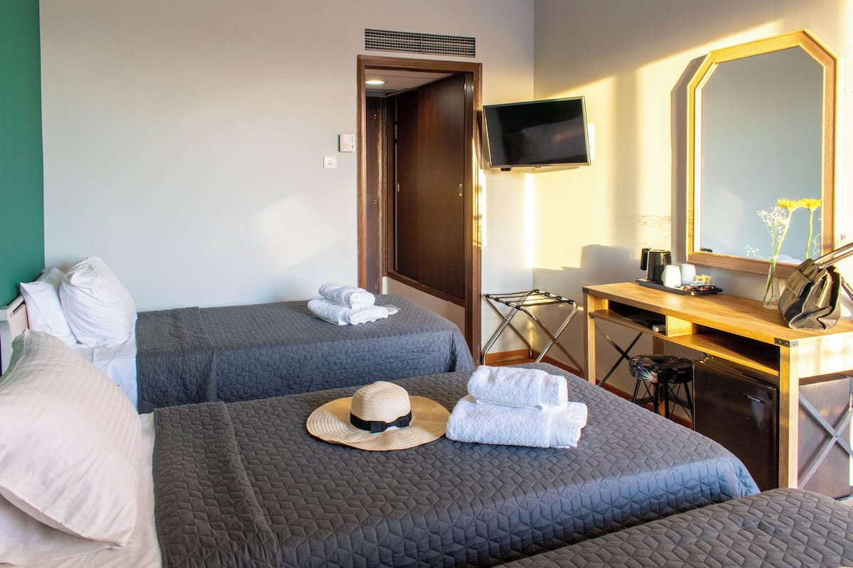 A hotel room with two beds, a desk, a TV, and a mirror.