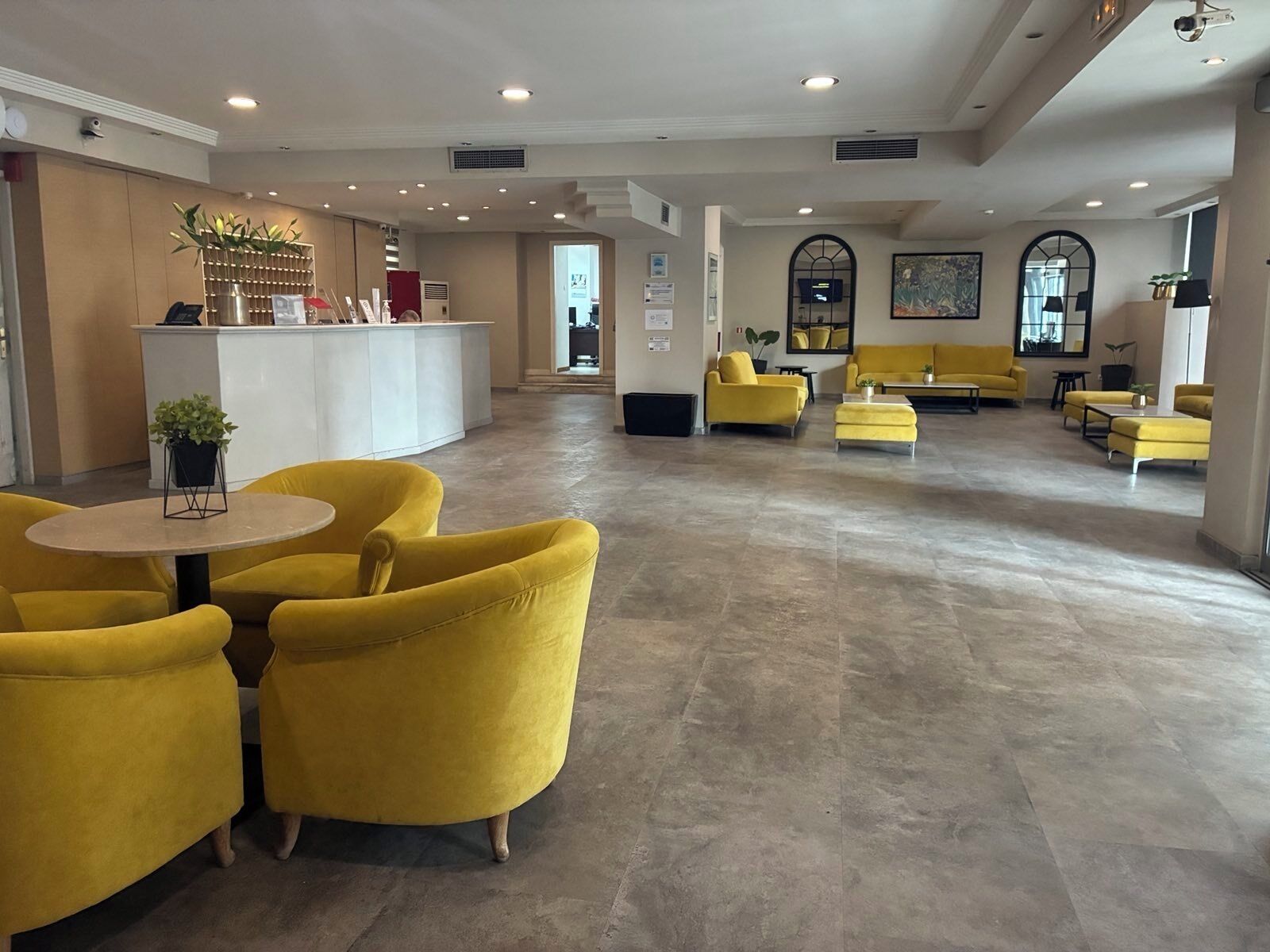A spacious lobby with yellow armchairs, a reception desk, and a modern interior design.