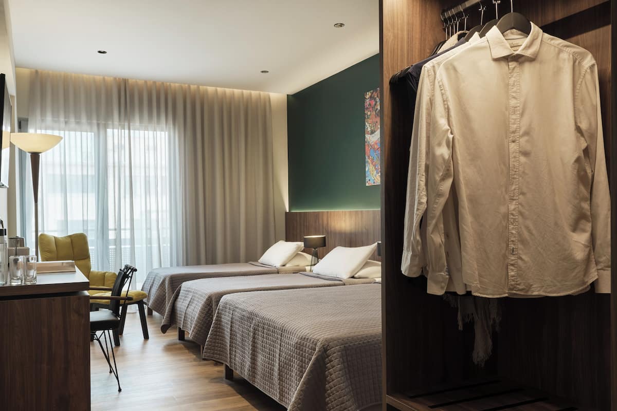 A hotel room with two beds, a desk, a chair, and a wardrobe.