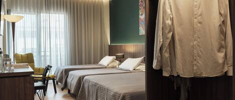 A hotel room with two beds, a desk, a chair, and a wardrobe.