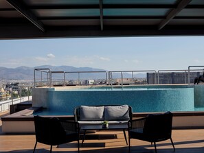 A rooftop pool with a view of mountains and a cityscape.