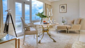 A spacious room with a large window, a round table, two chairs, a tripod, and a framed picture on the wall.