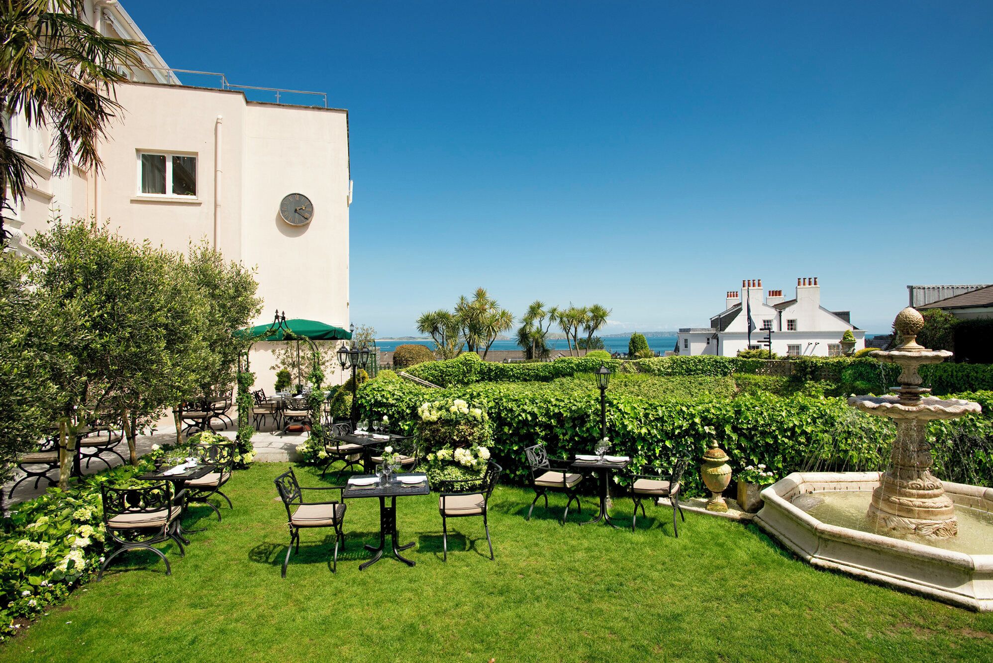 A courtyard with outdoor seating, a fountain, and a view of the sea.
