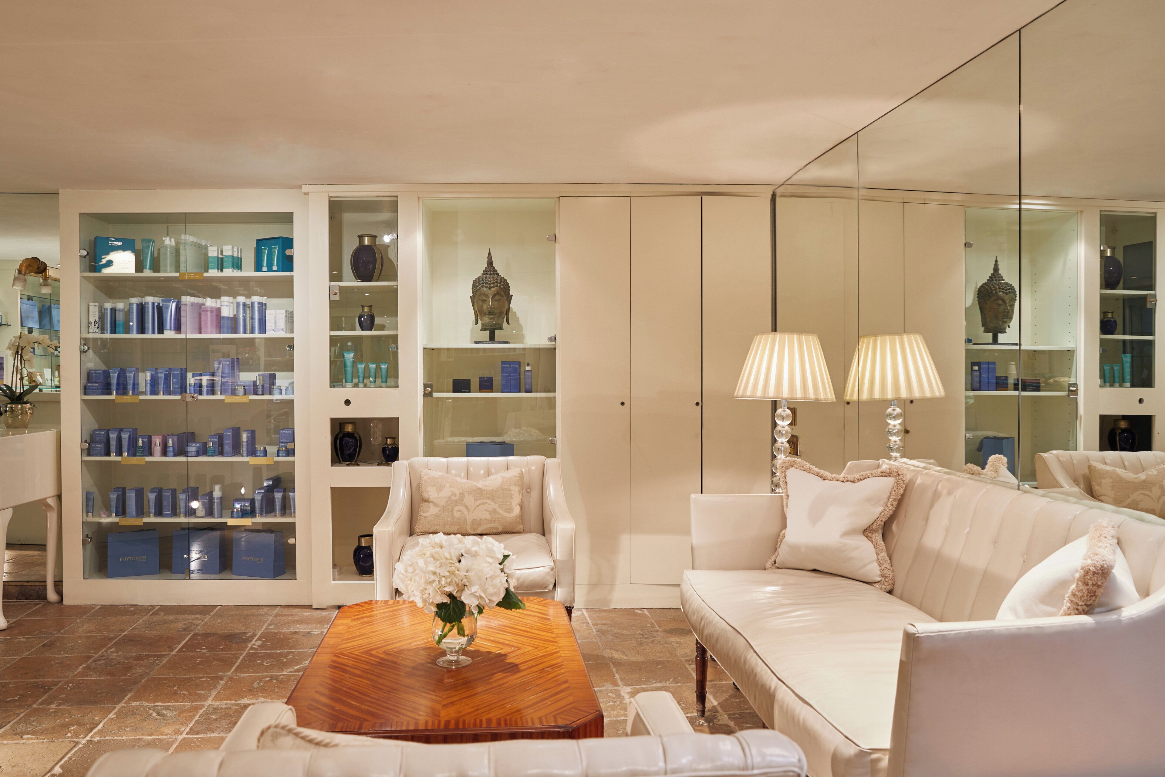 Un intérieur moderne avec un canapé blanc, une table basse en bois et une vitrine contenant divers objets.