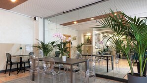 A modern conference room with glass walls, a wooden table, and clear plastic chairs. - Hotel Plaza Torino (Turin)