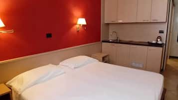 Una camera d'albergo con un letto, una piccola angolo cottura e una parete decorata in rosso.