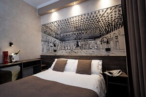 Camera d'albergo con un letto grande, un comodino, una lampada, un quadro appeso e una tenda.