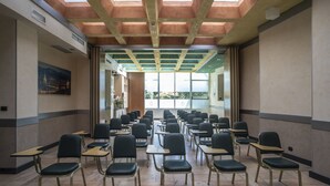 A conference room with rows of chairs and tables, large windows, and a high ceiling with skylights. - Hotel Plaza Torino (Turin)