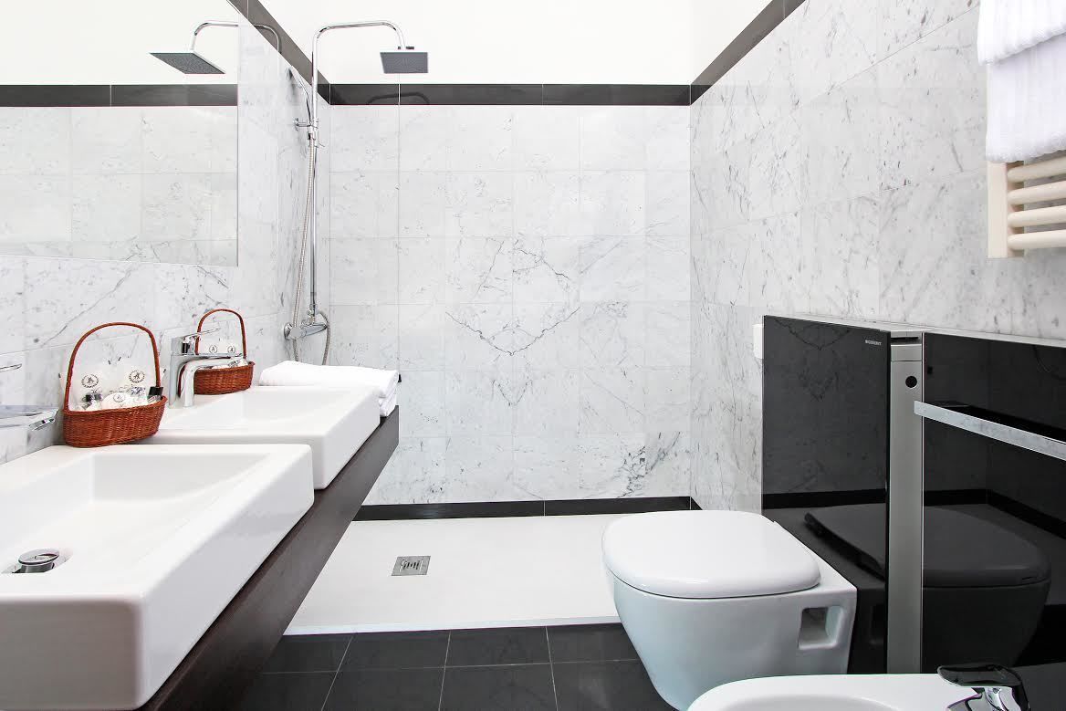Un baño moderno con tres lavamanos, ducha e inodoro.