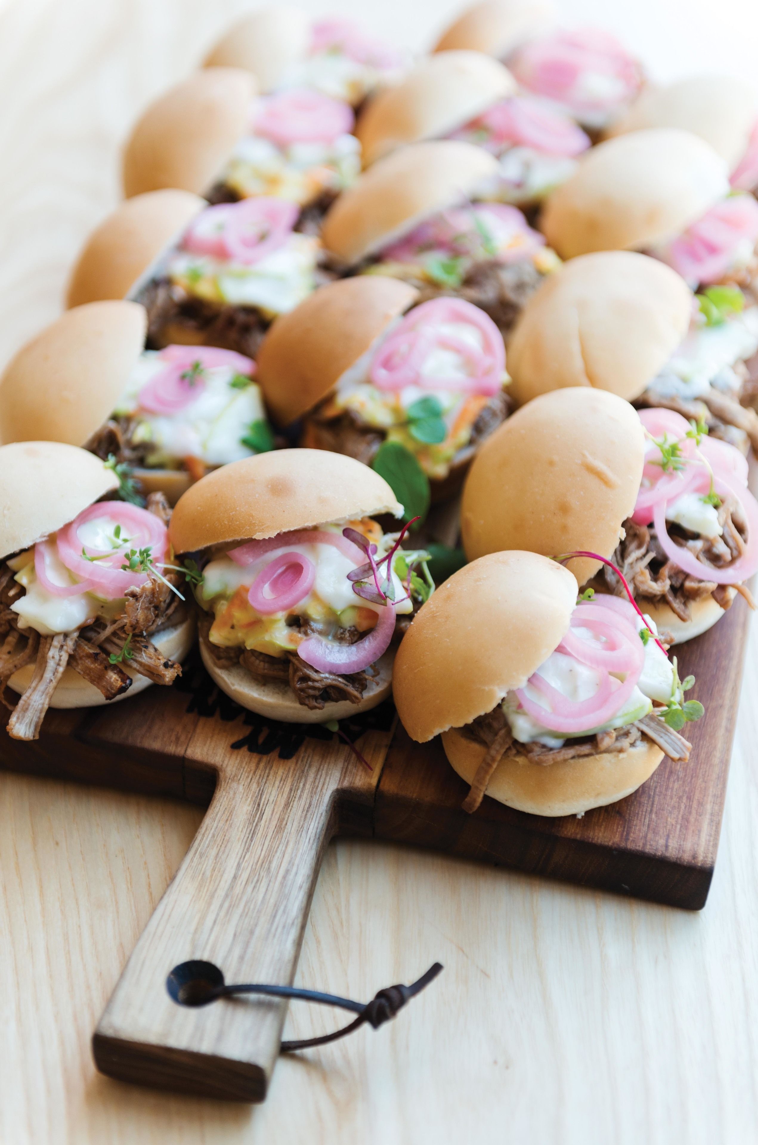 A wooden serving board with sandwiches.