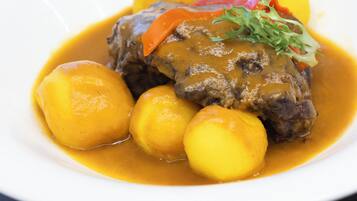 Une assiette de bœuf nappé de sauce et accompagnée de pommes de terre bouillies.
