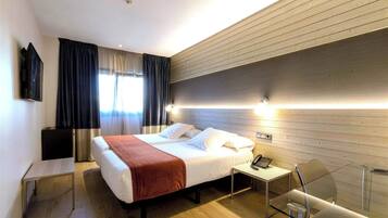 Una habitación de hotel con una cama grande, una mesita de noche y un escritorio con una silla.