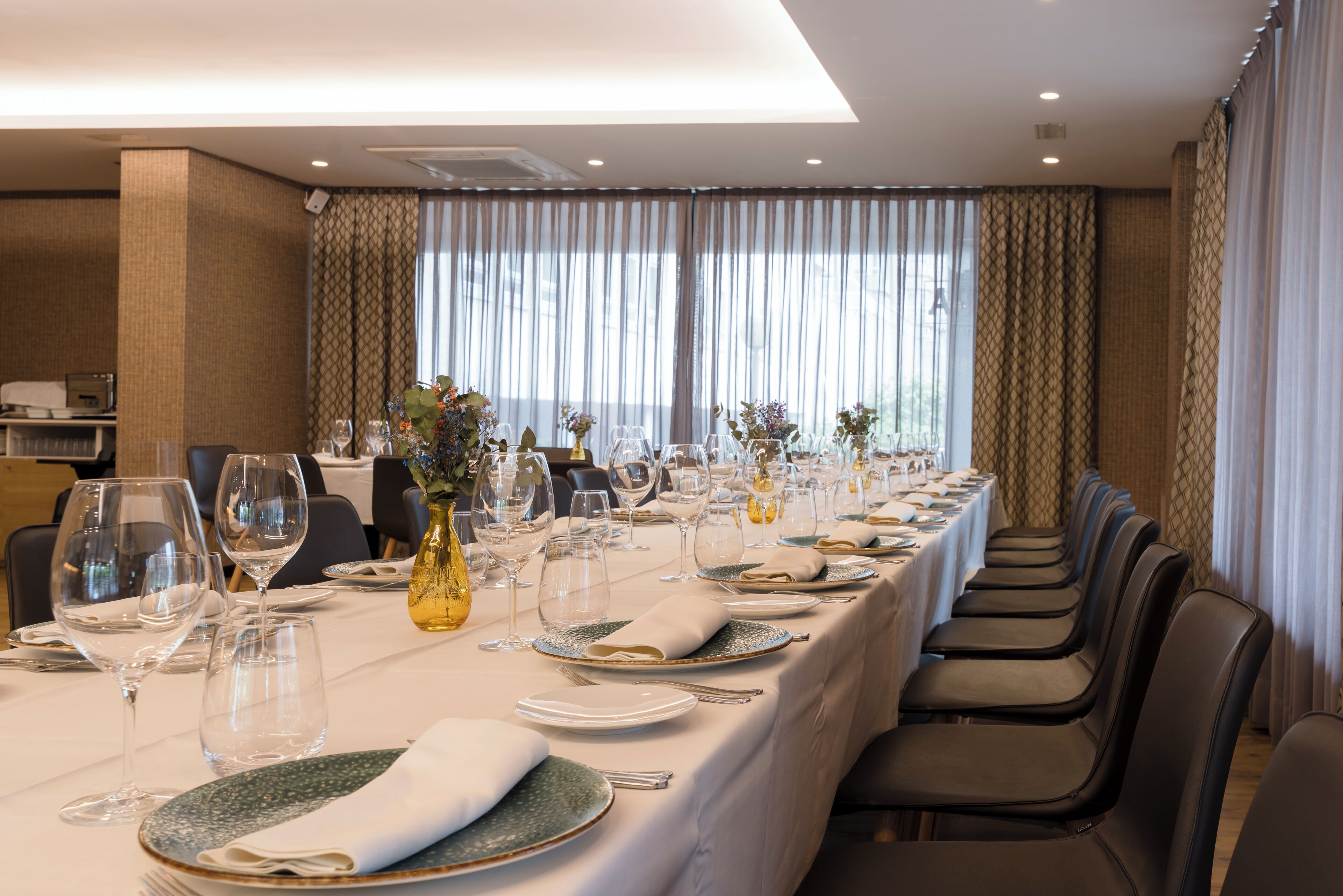 A long dining table set for a formal meal with multiple chairs, clear glassware, and neatly folded napkins.