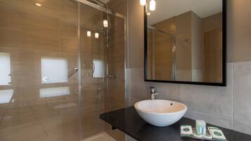 A modern bathroom with a glass shower enclosure, a white sink, and a large mirror.