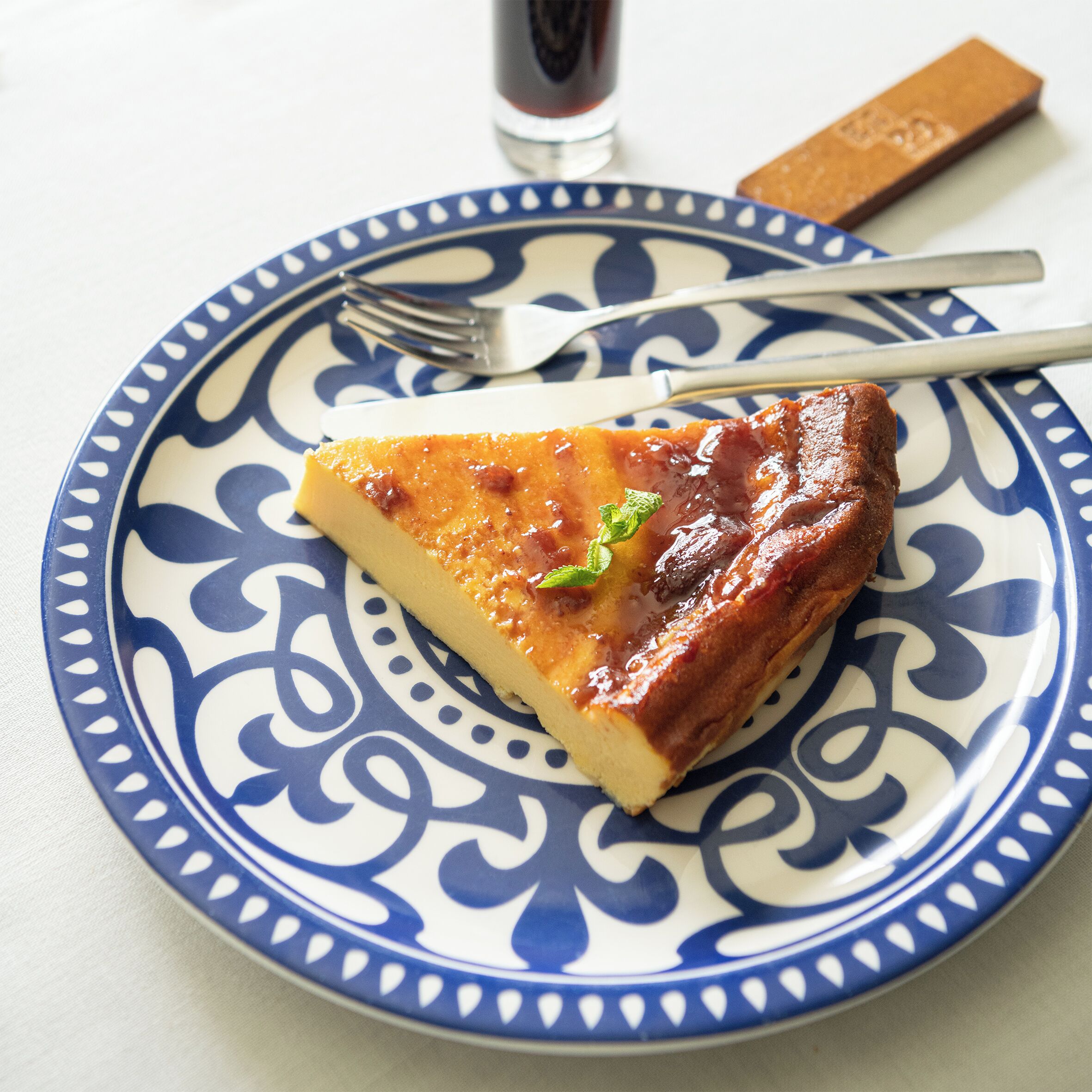 A slice of quiche on a decorative plate with a fork beside it.