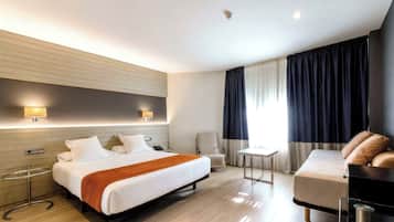 Una habitación de hotel moderna con una cama grande, mesitas de noche, un escritorio, una silla y un sofá.