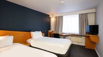 Une chambre d’hôtel avec deux lits, un bureau, une télévision et une fenêtre avec des rideaux.
