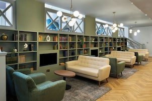 Eine moderne Bibliothek mit Bücherregalen, einem Flachbildfernseher und bequemen Sitzgelegenheiten.