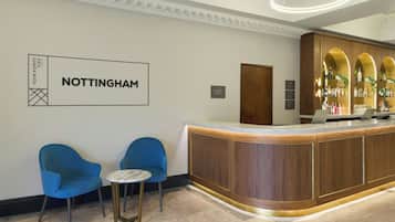 A reception area with a wooden counter, two blue chairs, a small round table, and a sign that reads 'NOTTINGHAM'.