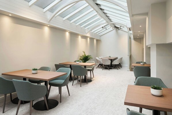 A modern interior with a high ceiling and skylight, featuring multiple tables and chairs arranged for dining or meetings. - Four Points Flex by Sheraton Nottingham (Nottingham)