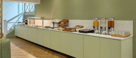 Un long comptoir de buffet proposant une variété de plats et de distributeurs de boissons.