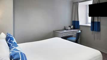 A hotel room with a bed, a desk, a chair, and a window with curtains.