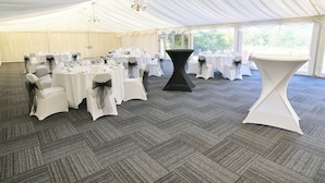 A tented event space with round tables, chairs, and a central black table.