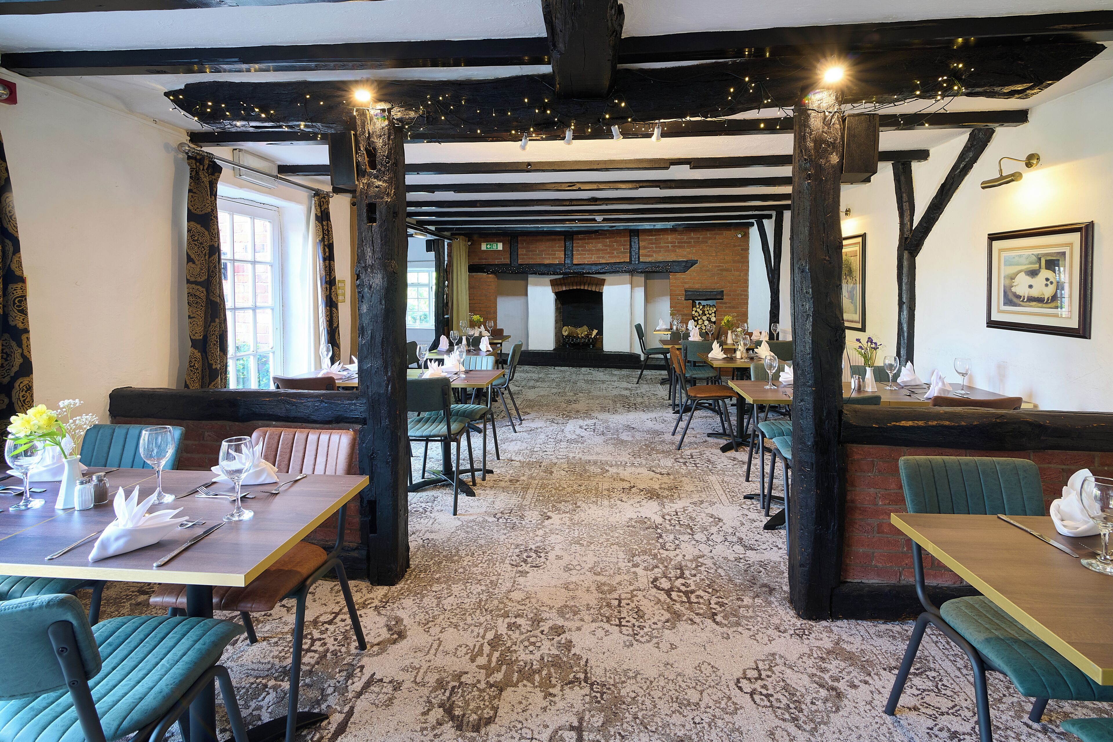 A restaurant with exposed beams, wooden tables, and chairs.