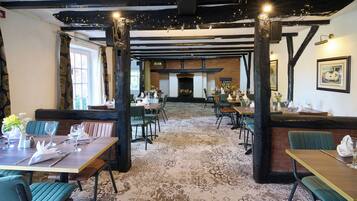 A restaurant with exposed beams, wooden tables, and chairs.