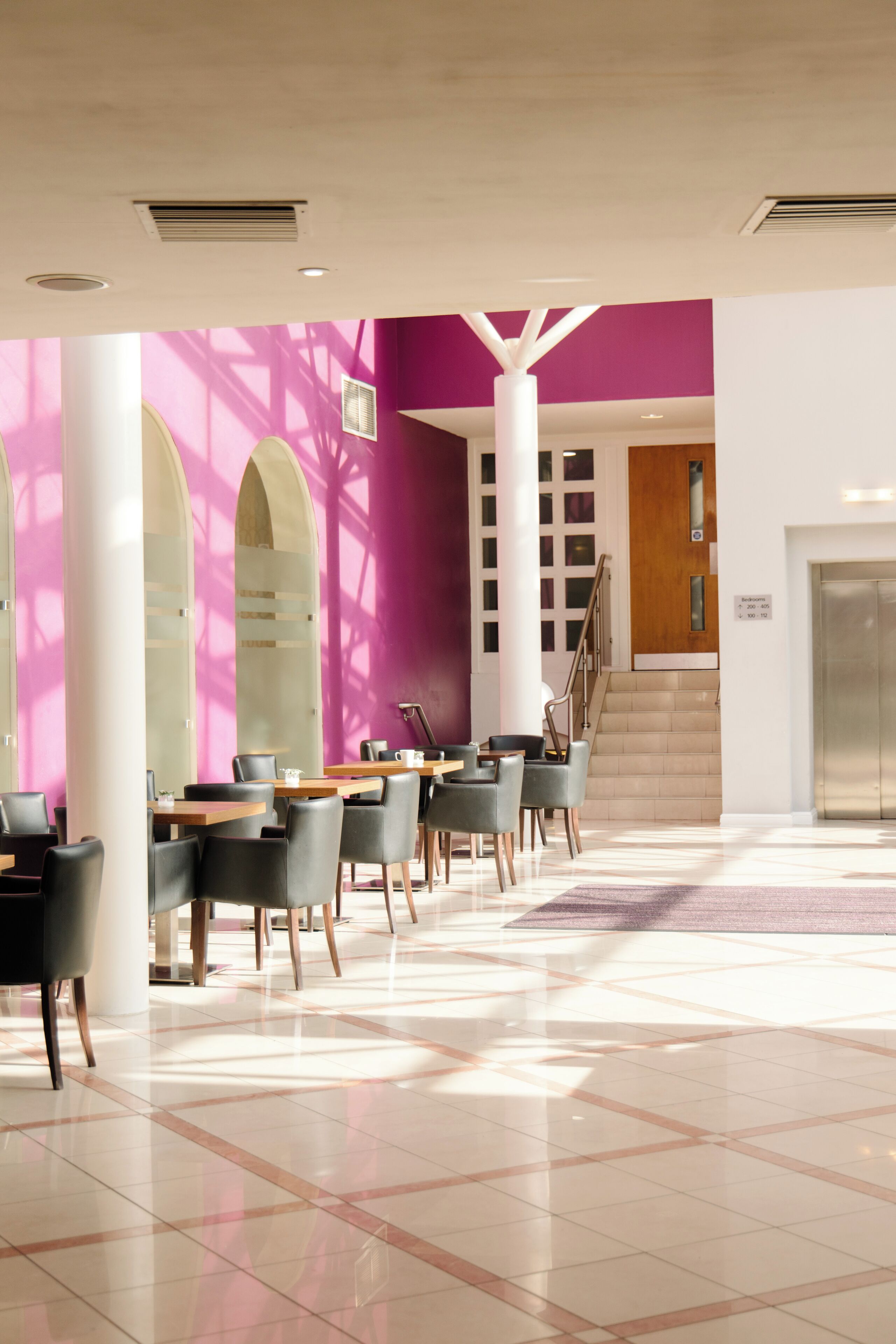 A modern lobby with a checkered floor, a staircase, and a reception desk.