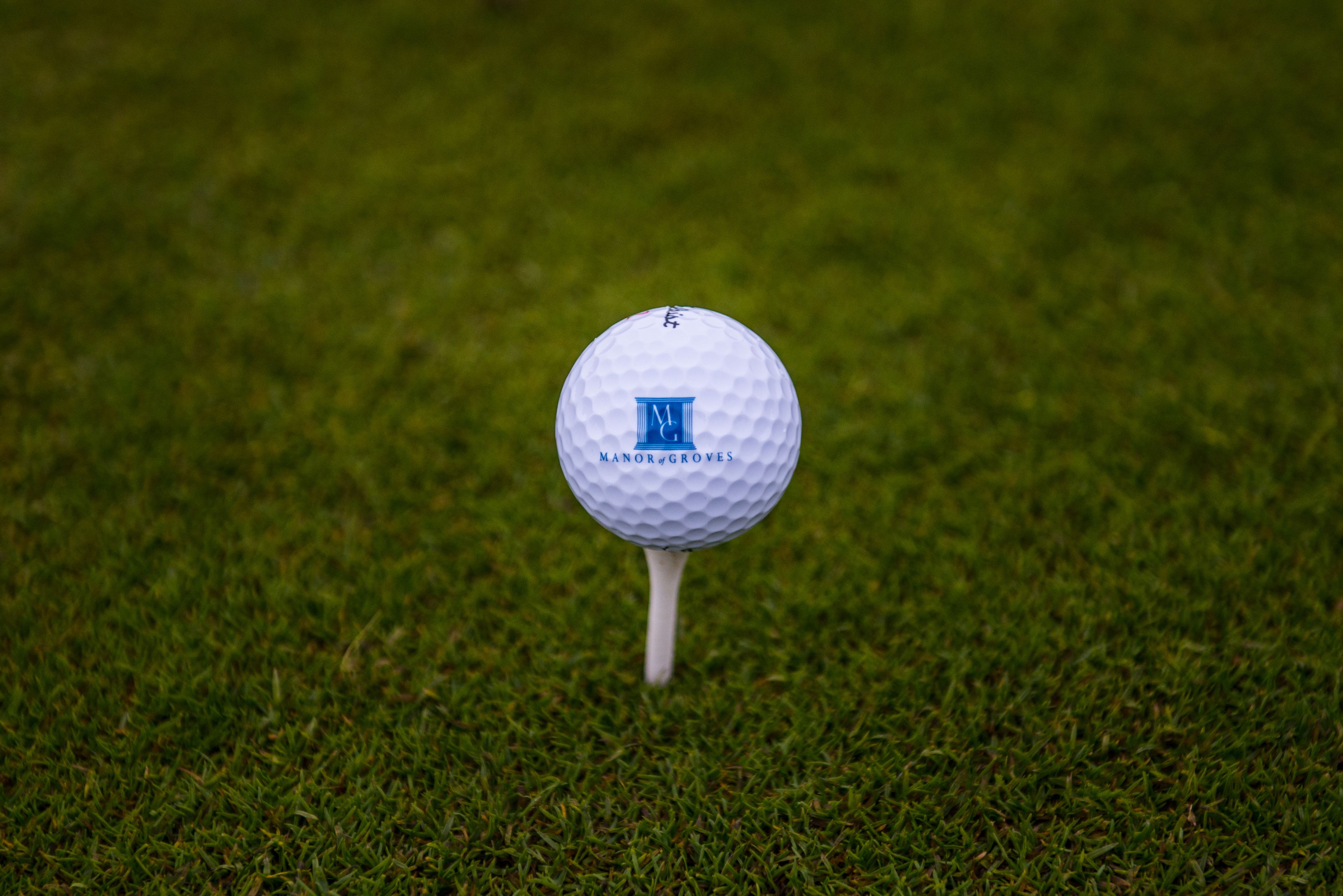 Una pilota de golf sobre un tee a un camp de gespa.