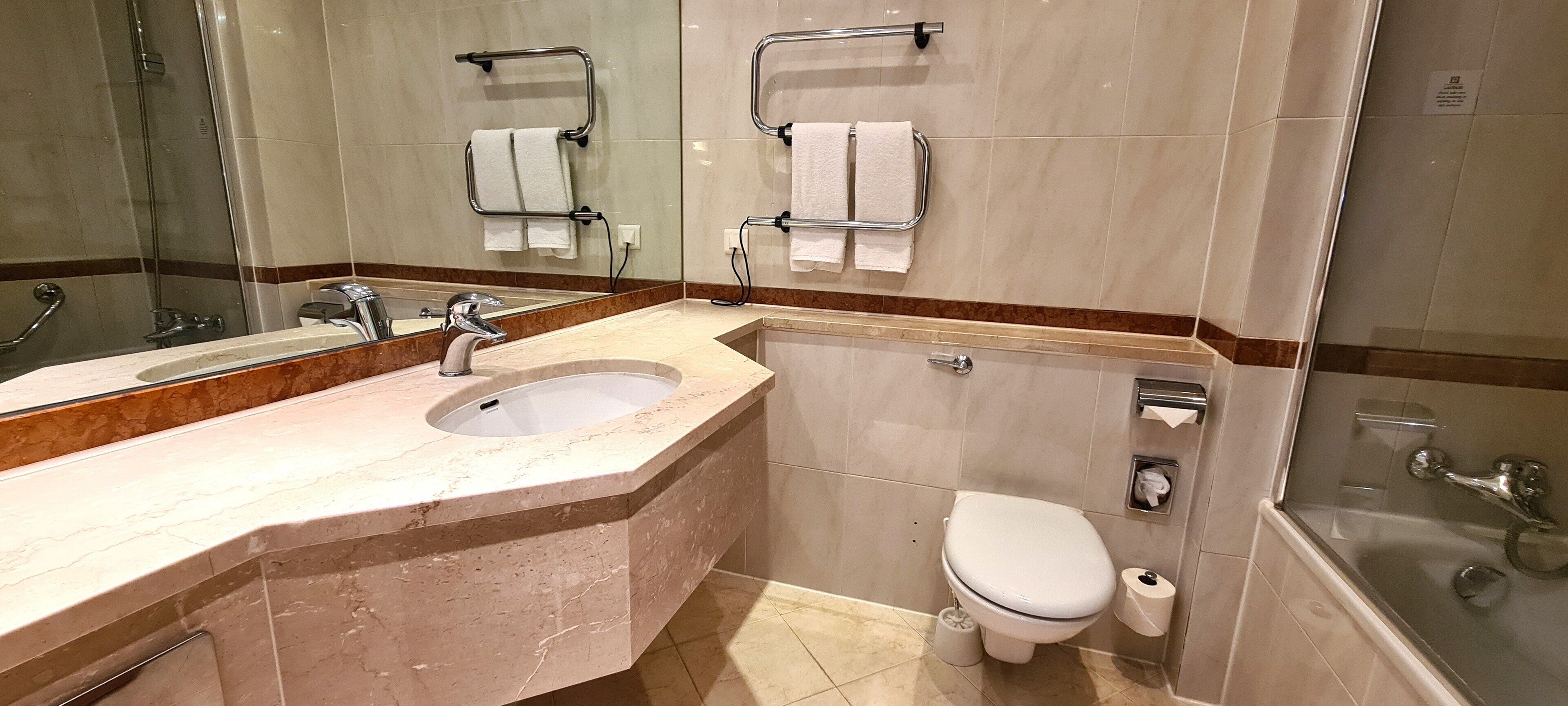 Un baño con lavamanos de mármol, inodoro y ducha.