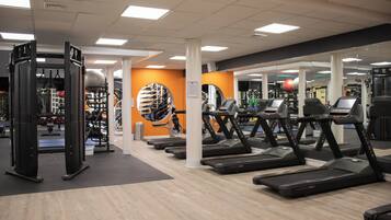 Ein Fitnessstudio mit Laufbändern, Kraftgeräten und einer Spiegelwand.